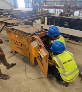 AMACO technicians in branded hi-vis repairing an Oscam rebar machine on site at a UAE fabrication yard